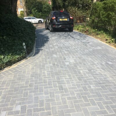 Large block paving driveway with curved edges installed by MUHAJ for vehicle access in North London