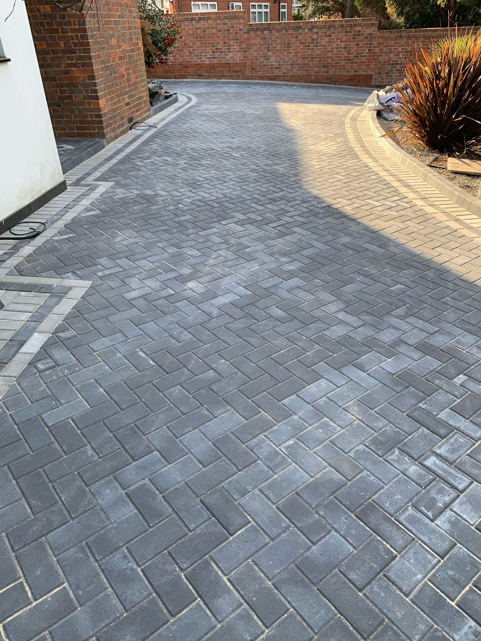 Curved edge block paving driveway with light and dark contrast finish by MUHAJ in Hertfordshire