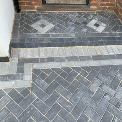 Decorative block paving entrance with patterned doorstep and contrasting border by MUHAJ in Greater London