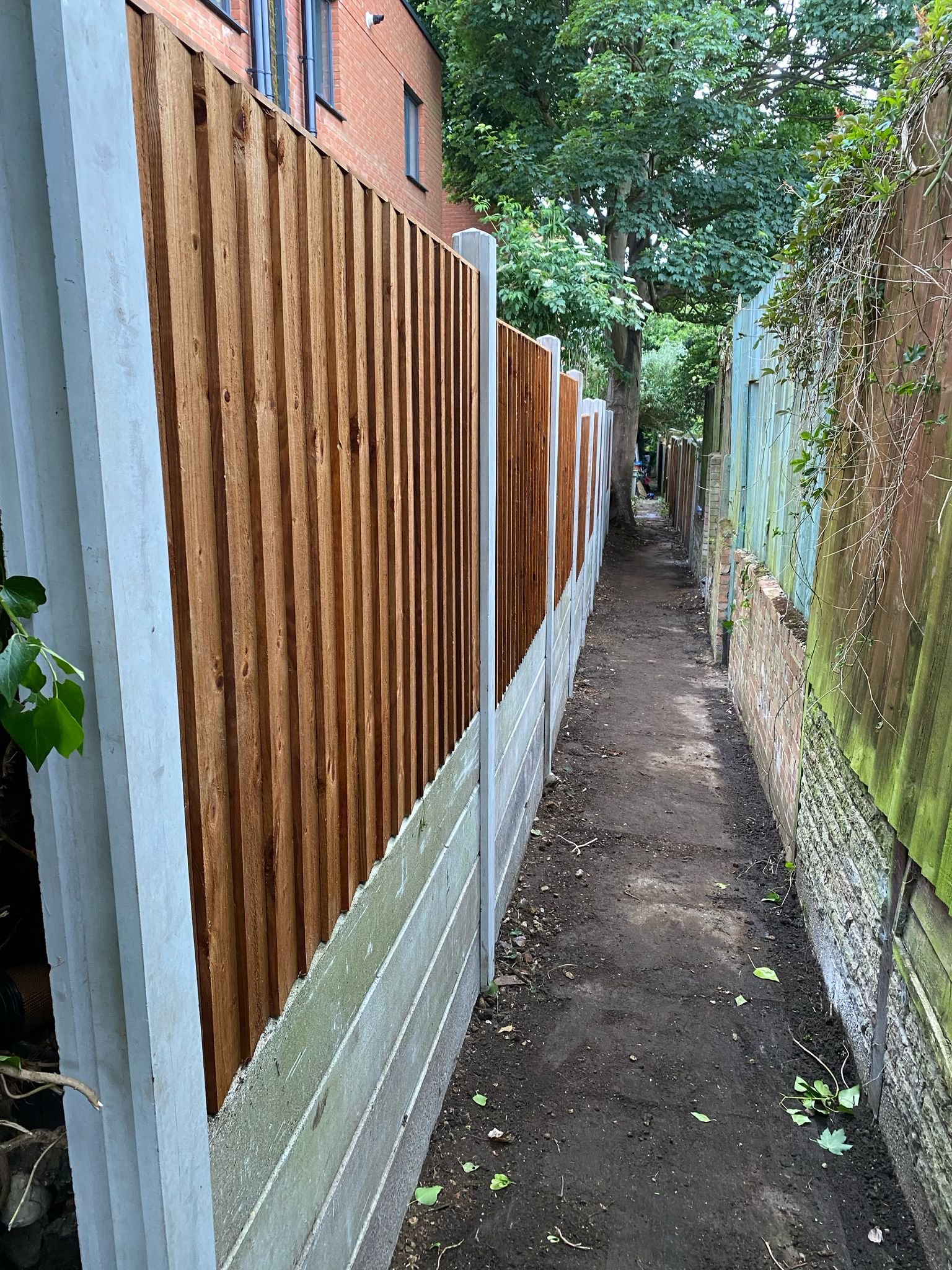 Concrete gravel board fencing with vertical timber panels installed by MUHAJ in narrow alleyway in Harrow